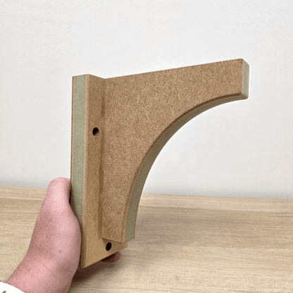 Shaker Gallows Bracket displayed in hand, showcasing the precision cut and moisture-resistant material ideal for shelving.