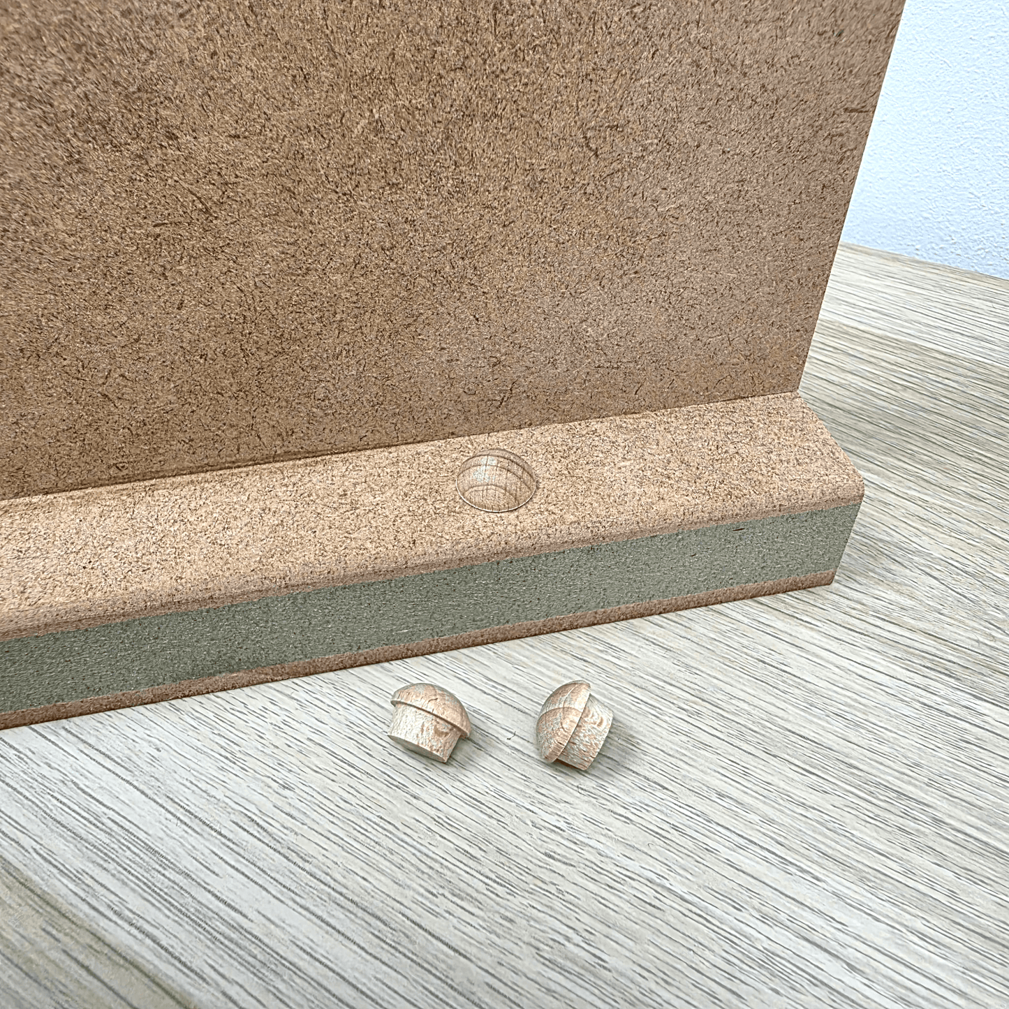 Shaker Gallows Bracket components including a backplate and wooden mushrooms on a wooden surface.