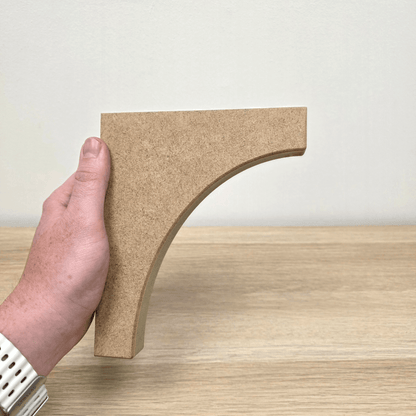 Traditional Shaker Shelf Bracket held in hand, showcasing its elegant design against a wooden background.